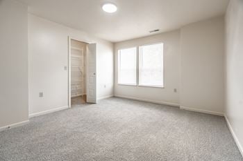 A room with a carpeted floor and a door leading to another room